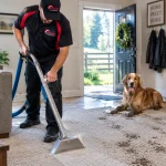 How to get mud out of carpet: technician cleaning muddy paw prints by a back door as a golden retriever watches
